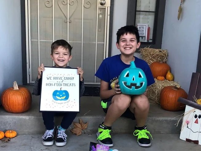Kids waiting for the autistic child with candies and other goodies holding blue pumpkinin Halloween